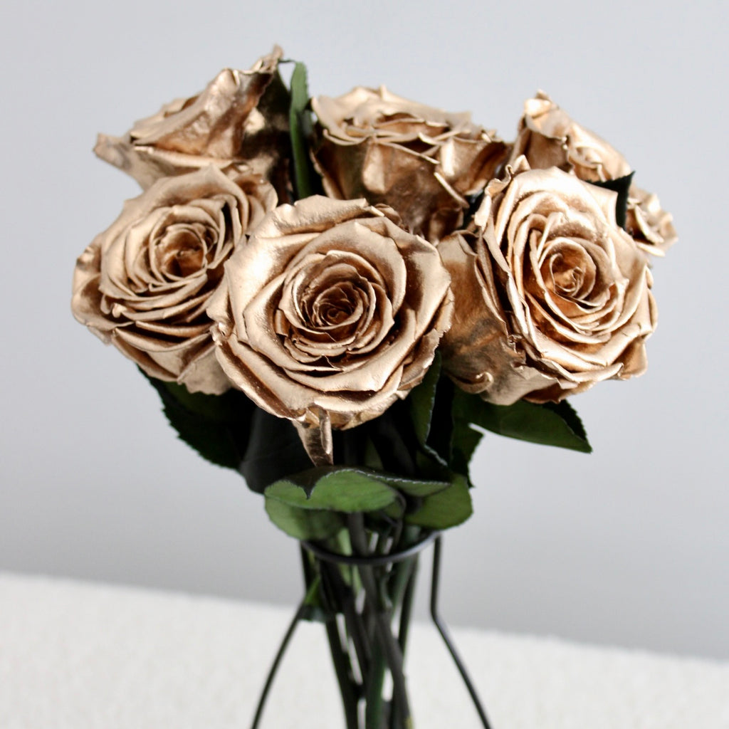 Bouquet of gold Infinity roses, featuring multiple metallic golden roses with shimmering petals that reflect light, arranged together to create a luxurious and elegant display. The roses' radiant finish highlights their timeless beauty and durability.